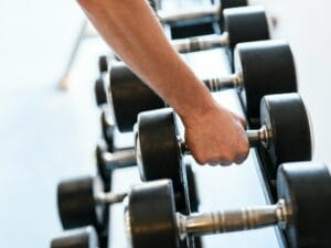 man reaching for dumbells