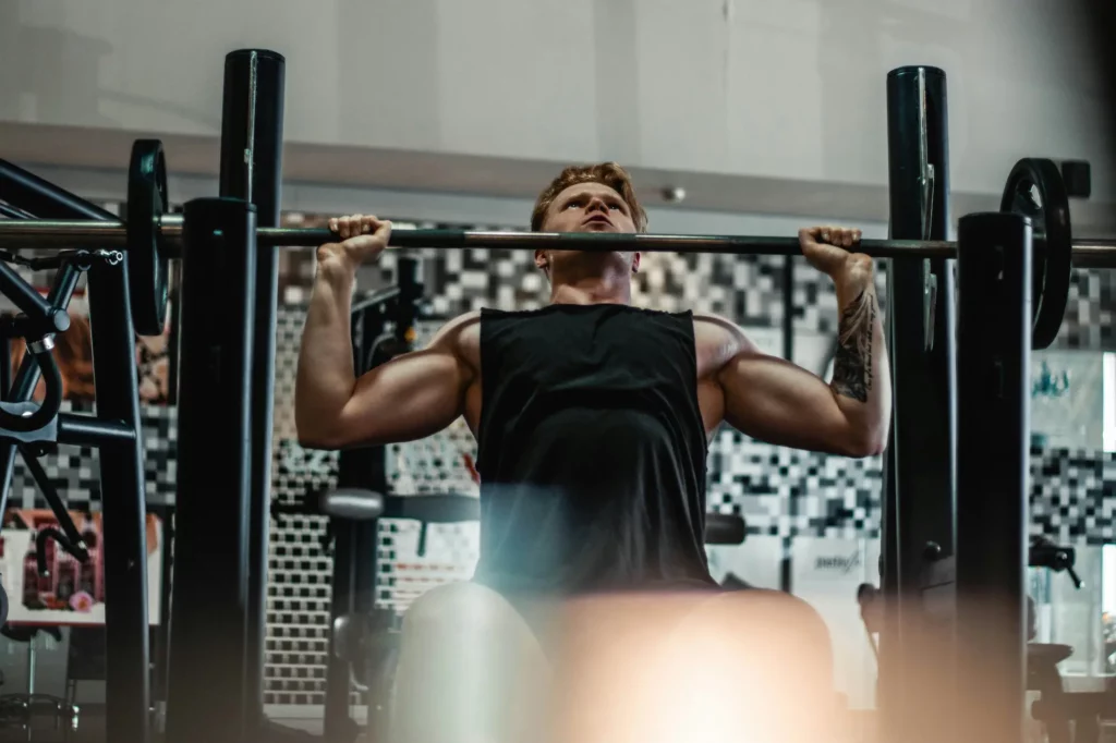 A man performs a pull-up on a bar in a gym