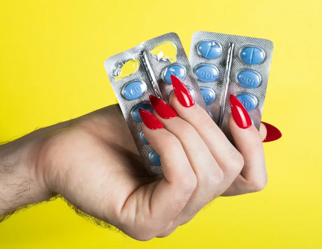 Woman's hand holding blister pack of blue Viagra pills