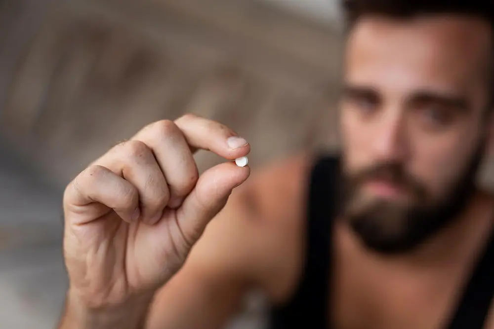 Young men holding Anadrol tablet in hand 