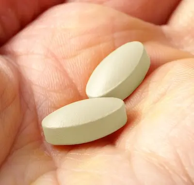 Hand holding two pills of Stendra (avanafil)